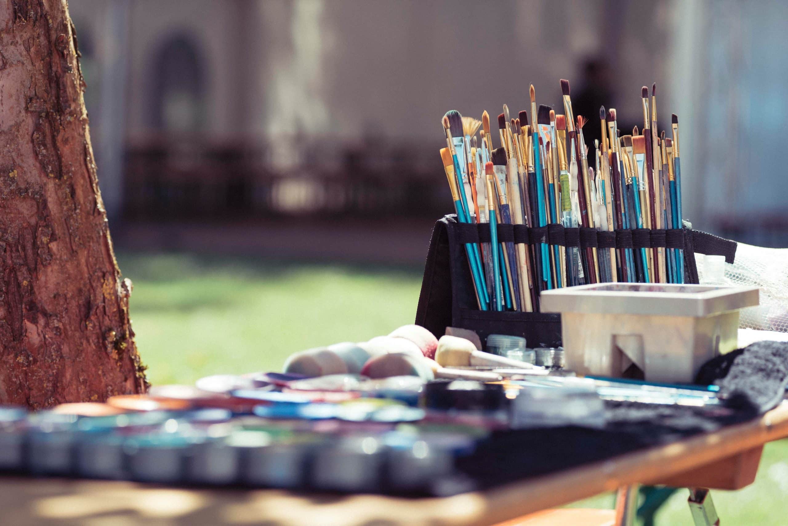 Image illustrant une table avec pinceaux et tubes de peinture en plain air