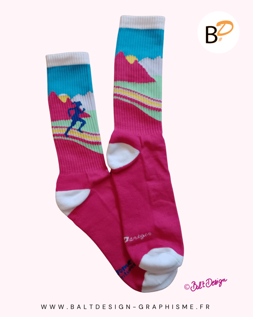 Paire de chaussettes illustrées. Femme courant dans les sentiers de montagnes. Couleurs vives : rose, bleu, jaune.