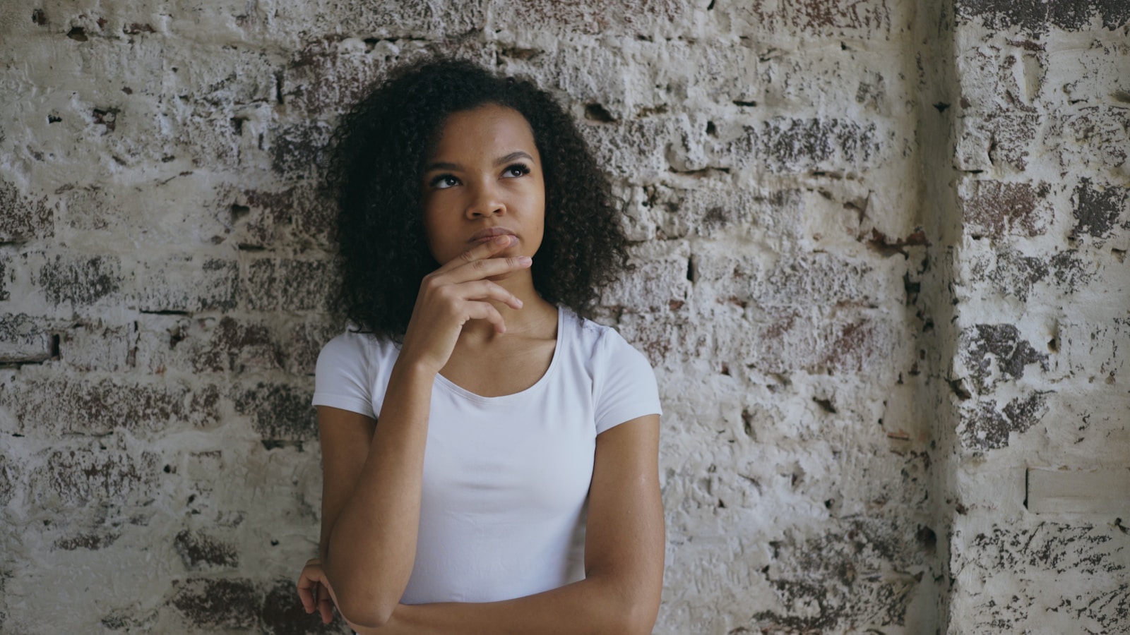 Young woman with hand on chin thinking